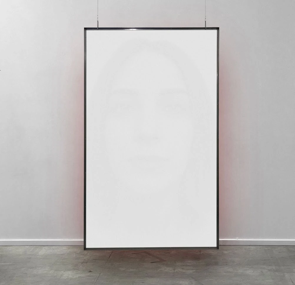 A pale suspended portrait with a subtle red reflection