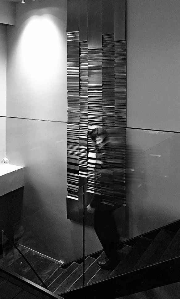 Side installation view of a long reflective steel relief