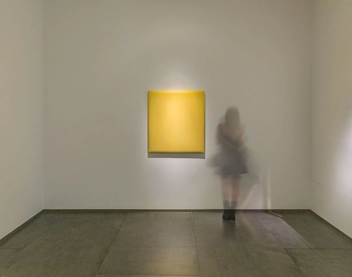 A yellow PE-HD work installed in a gallery with a viewer passing